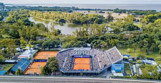 Aerial view of the Buenos Aires ATP 250 (Argentina Open), showing the main clay court packed with spectators, surrounded by green parkland and nearby courts.