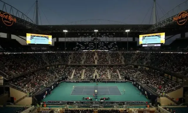 Miami Open center court inside Hard Rock Stadium — a tennis surface laid over a football field, known for its slower conditions and shadow effects compared to the outer courts